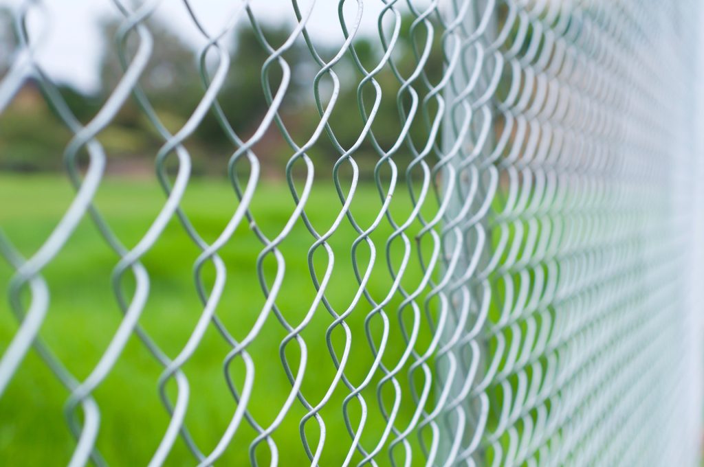 Close up chain link fence surrounding a green field with trees Malibu California